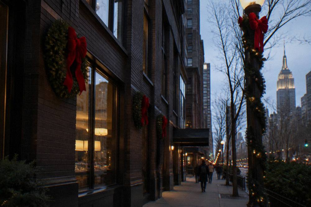 Festive wreaths and red ribbons decorating a Midtown street corner at dusk