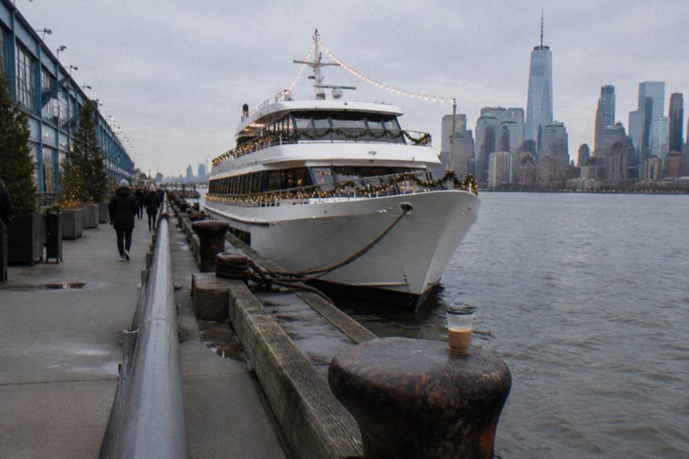 A decorated yacht with string lights moored at Chelsea Piers