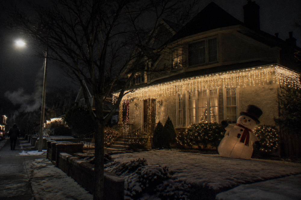 A Brooklyn residential street lined with large illuminated holiday house displays at night