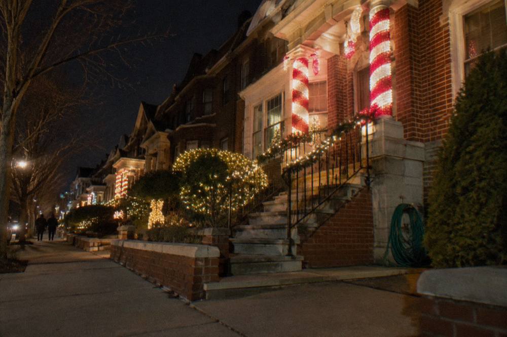 Brooklyn rowhouses covered in oversized glowing Christmas light displays at night