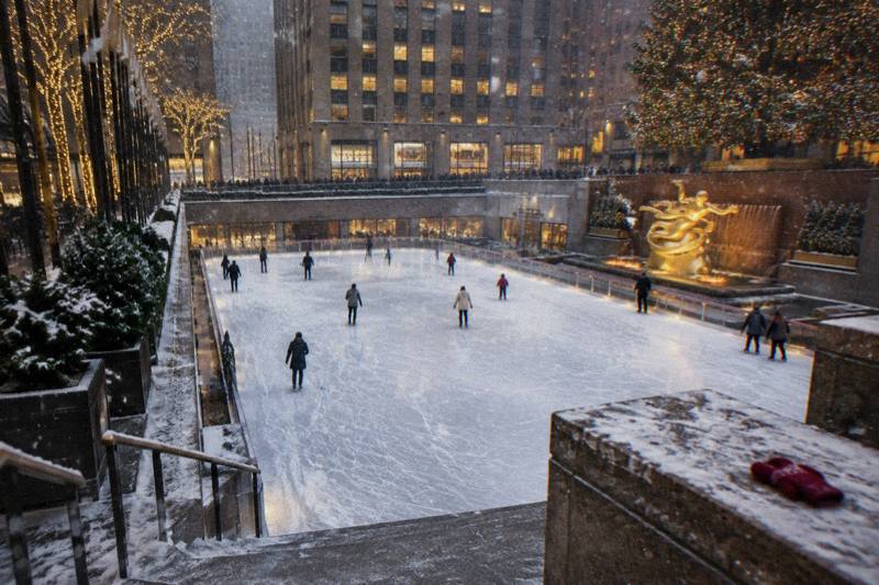 Skaters gliding across an outdoor Midtown Manhattan rink beneath the Rockefeller Center tree