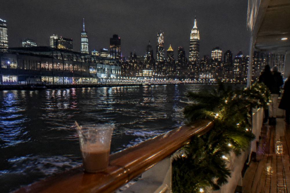 Passenger yacht on a night harbor cruise passing a brightly lit city skyline