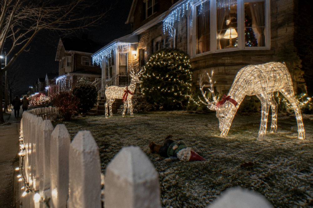 A brightly lit Brooklyn street lined with extravagant holiday displays and life-size decorations