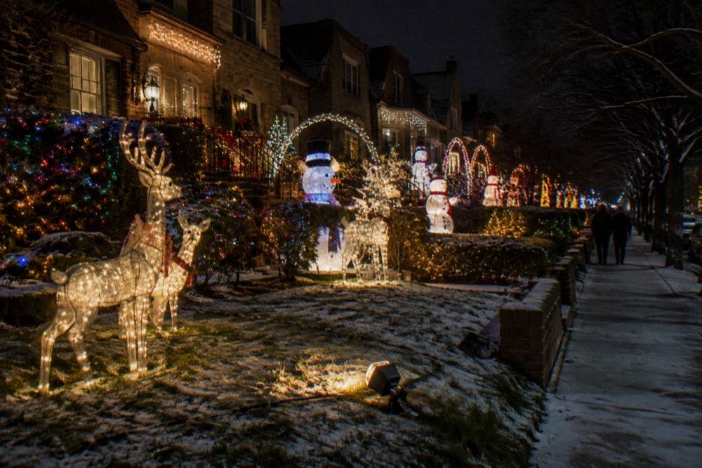 Row of Brooklyn houses covered in illuminated reindeer and oversized holiday displays at night
