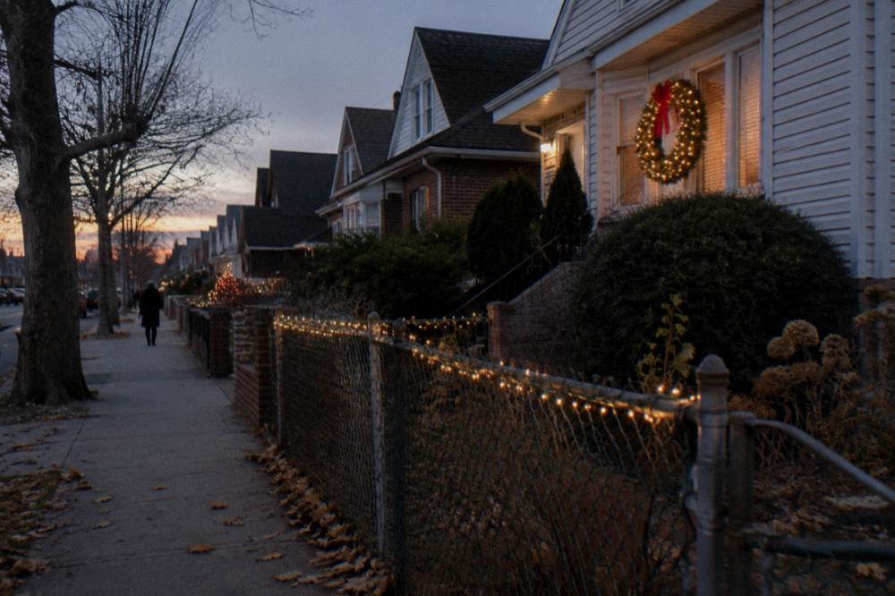 Festively lit residential street in Dyker Heights with string lights and holiday figures
