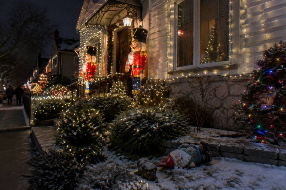 Ornate house front covered in Christmas lights and holiday figures at night