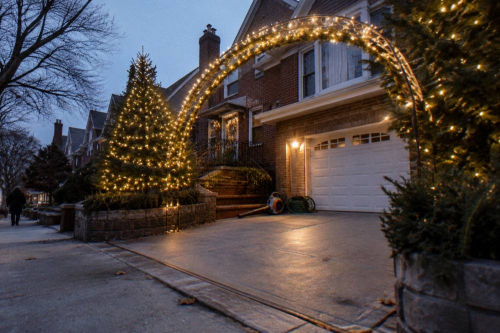 Evening view of a decorated Dyker Heights block with glowing arches and lit trees