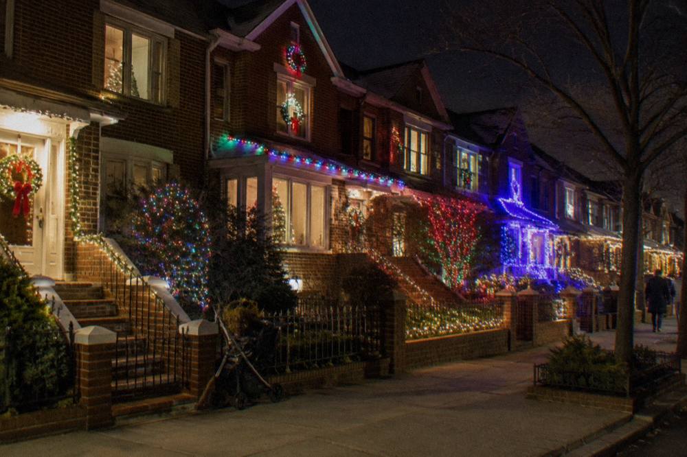 A row of festively lit Brooklyn row houses decorated for the holidays at night