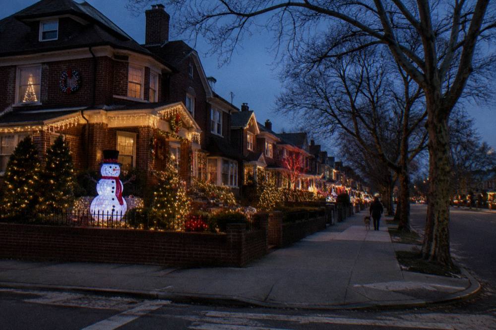 A Brooklyn street corner glowing with dense holiday light displays on row houses at dusk