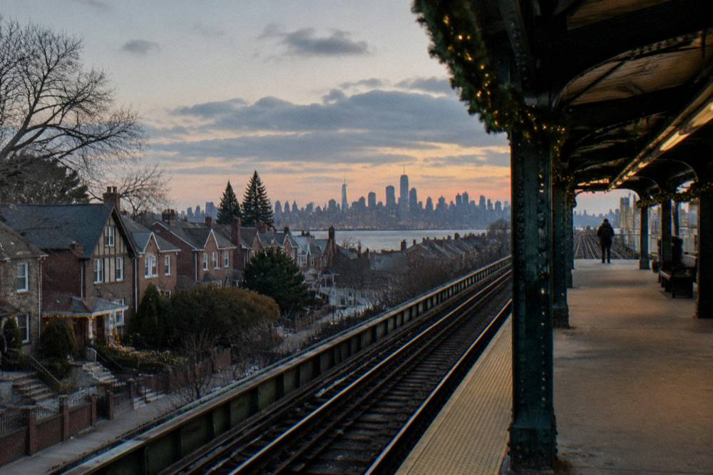 A subway platform sign and evening street in Brooklyn during the holiday season