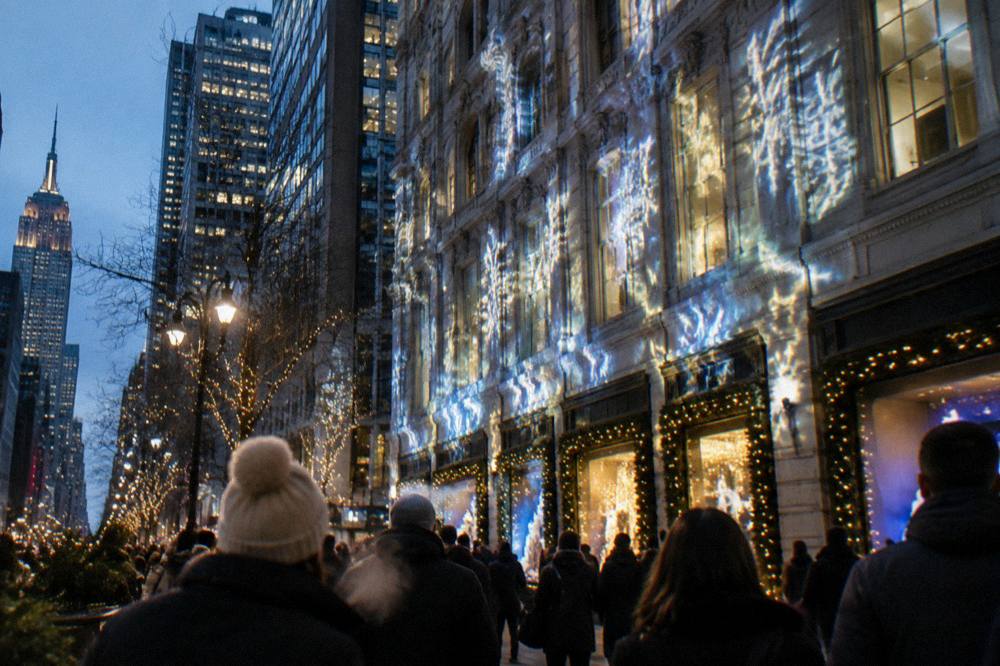 Festively lit department store facade with animated light projections above a crowded avenue
