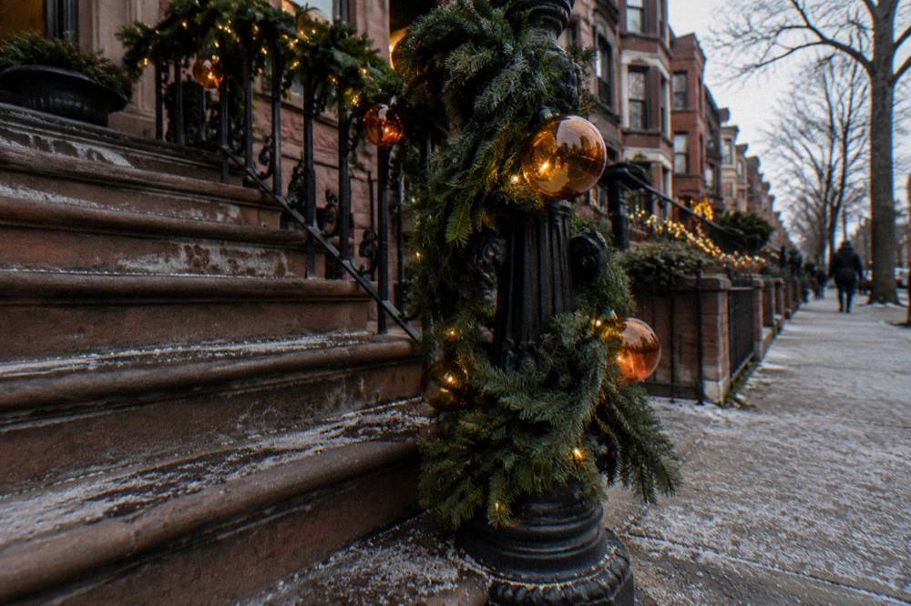 Close view of a holiday-decorated Brooklyn stoop with glowing ornaments and lights