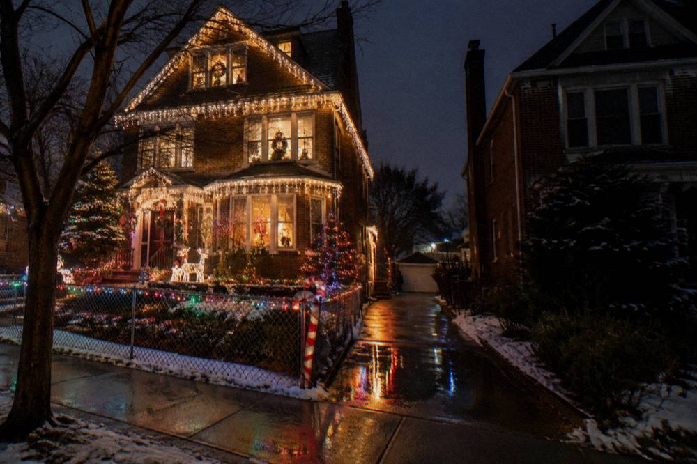 Brooklyn block of rowhouses covered in colorful Christmas lights after dark