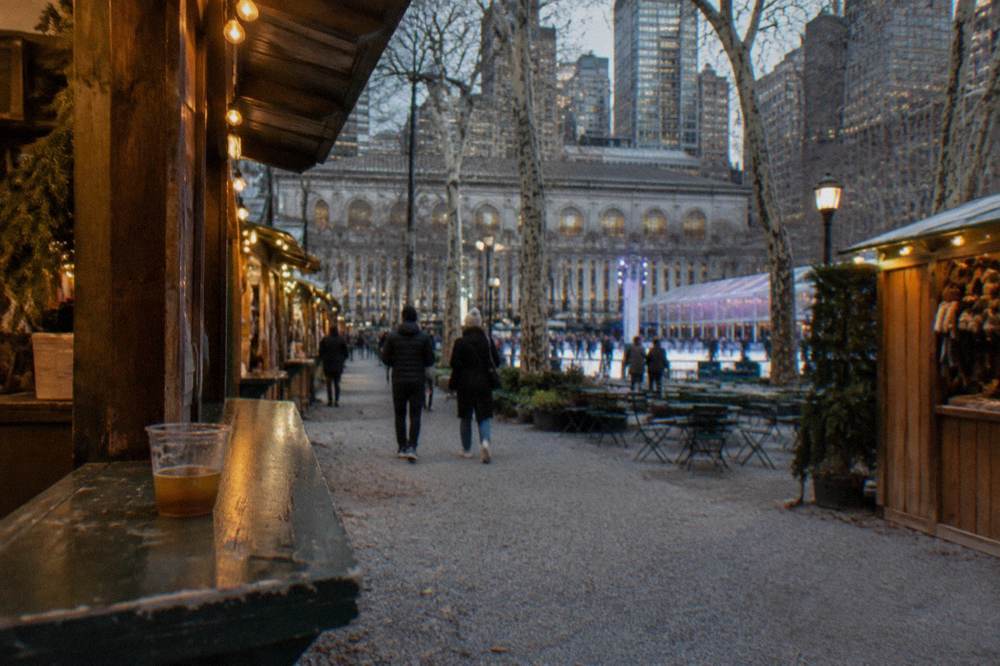 Wooden market stalls strung with lights in a Manhattan park on an evening