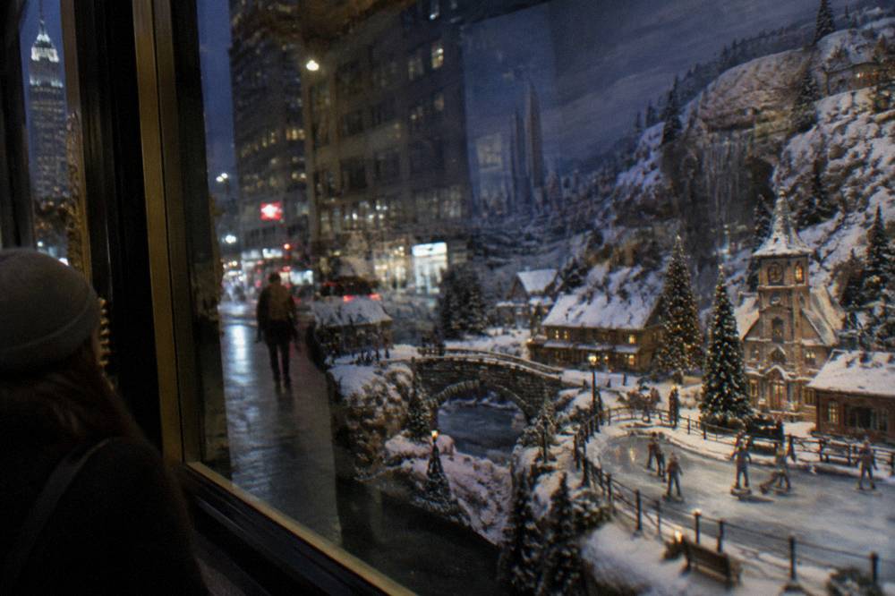 An elaborately decorated holiday display window with a winter scene behind the glass