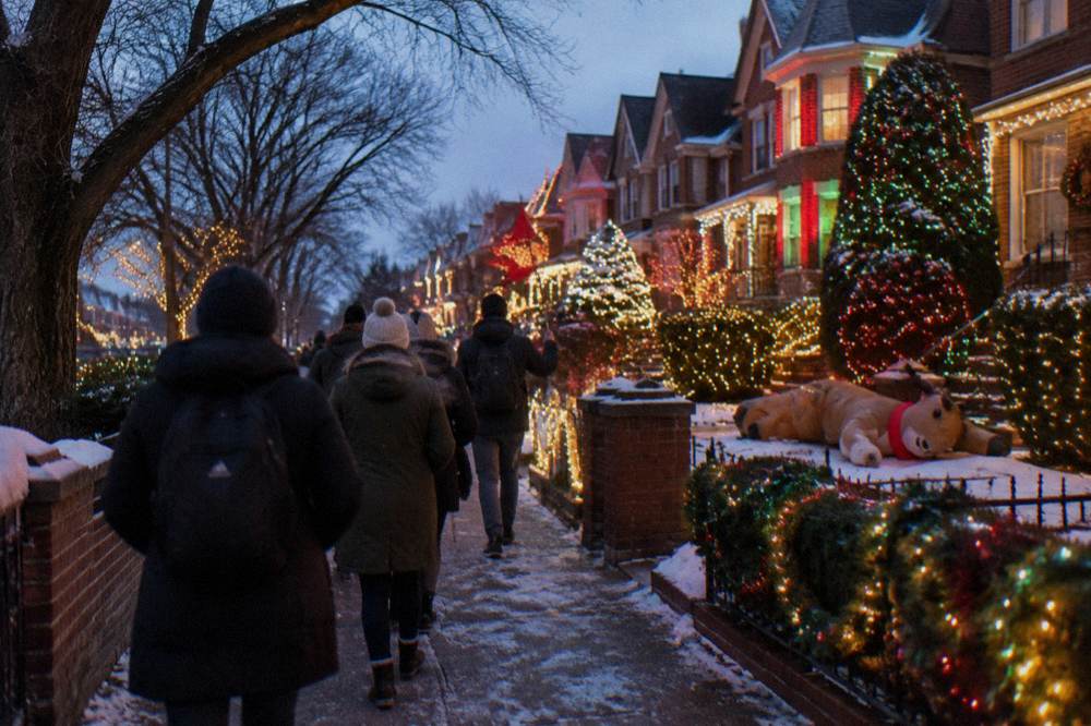 A guide holding a small flag leading a group of walkers past lit holiday displays on a residential street