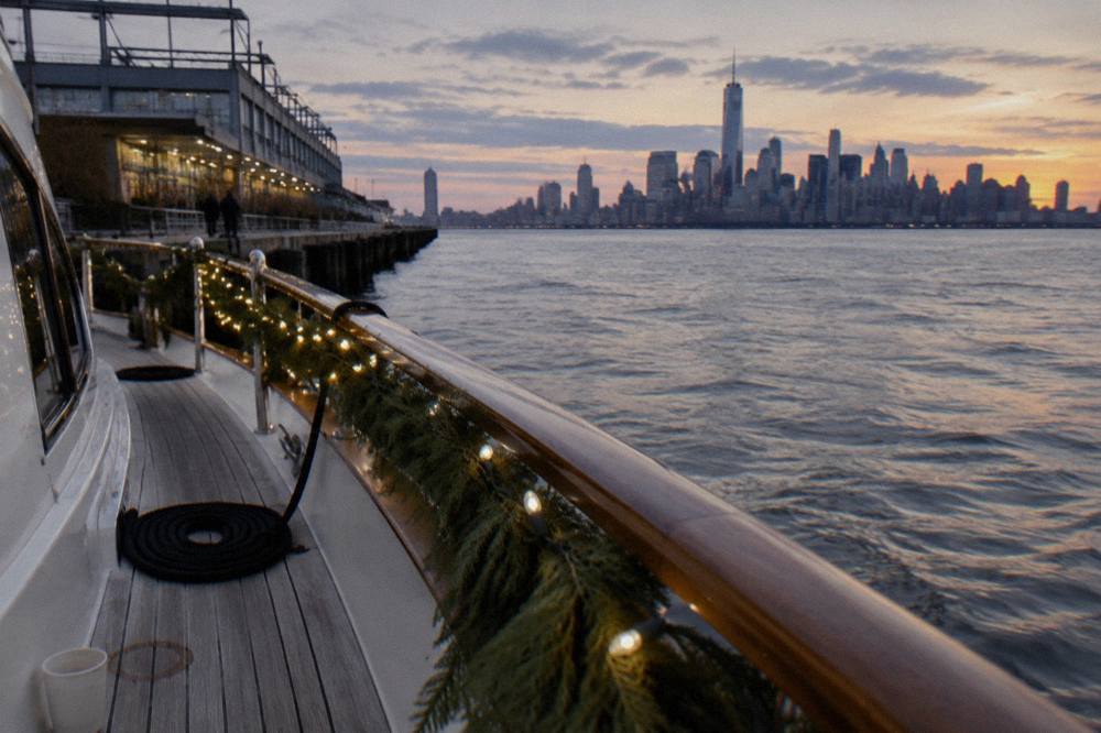 Holiday string lights and garland along the railing of a yacht moored at a Manhattan pier