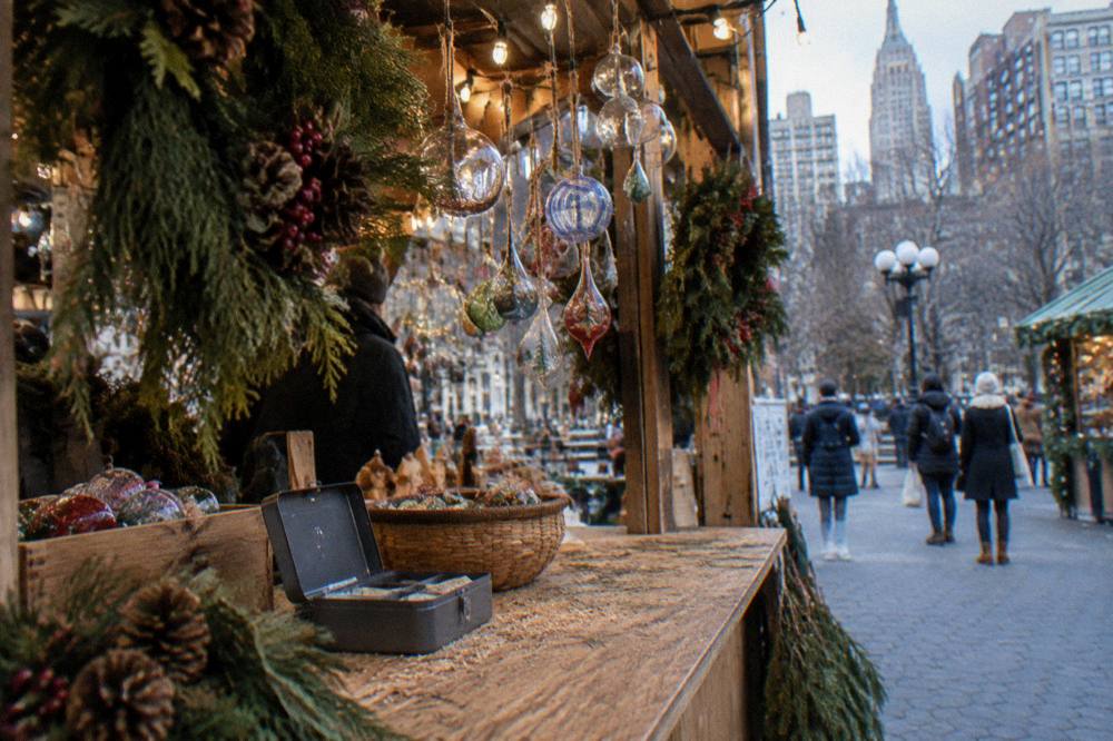 Market stalls displaying handmade ornaments and wreaths under strings of warm white lights