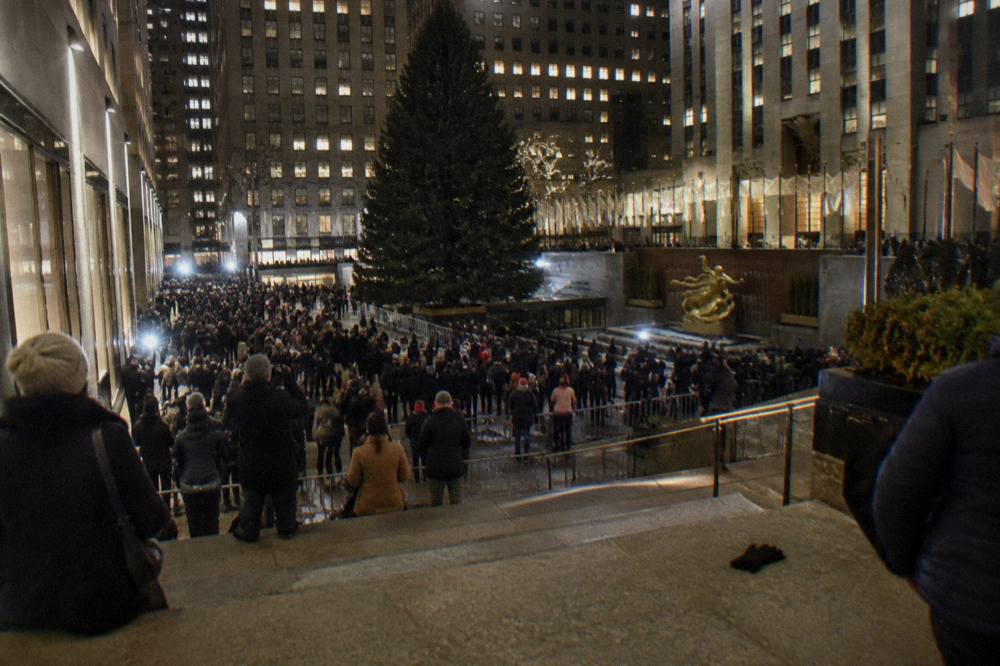 Crowds gathered in Rockefeller Center plaza at night waiting for the Christmas tree lighting