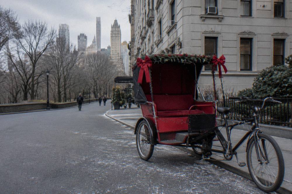 A festively decorated pedicab sleigh with string lights waiting on a Midtown street at dusk