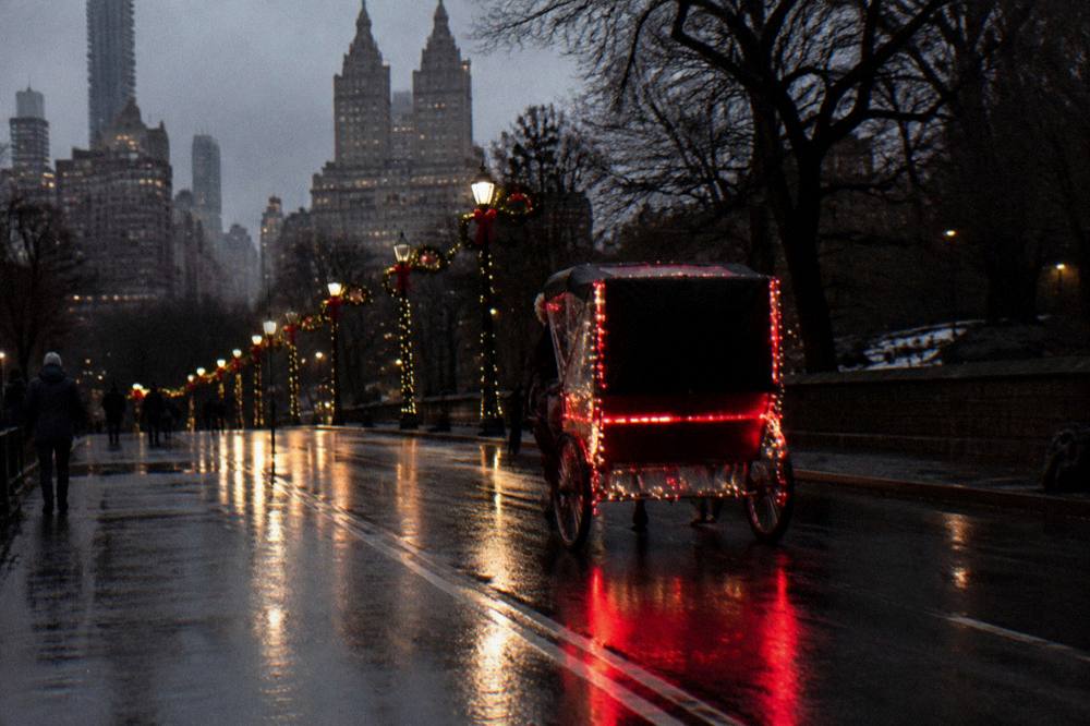 A lit rickshaw sleigh moving along a festive Midtown avenue at night with holiday lights overhead