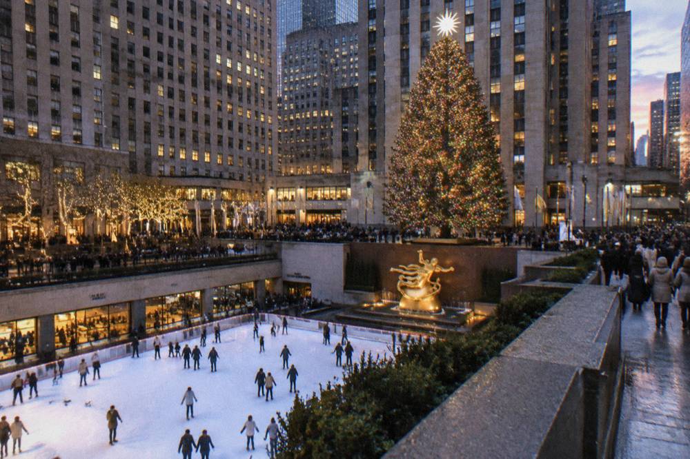 Rockefeller Center plaza at dusk with the Christmas tree glowing above the ice rink
