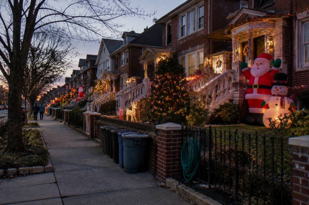 Row of Brooklyn houses covered in elaborate Christmas light displays at night